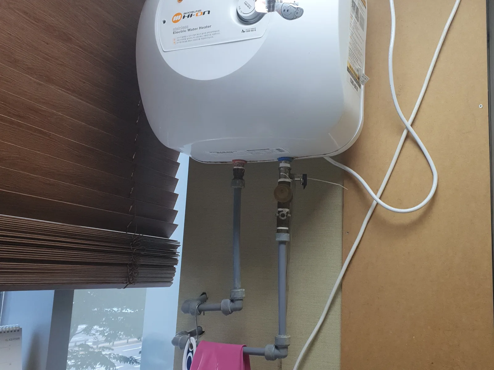 사무공간 벽면에 설치된 노후 전기온수기, 교체 작업 전